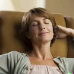 A woman relaxes in a comfortable chair as she listens to an online hypnotherapist